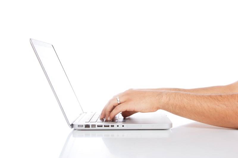 Hands and a white laptop on a white background.